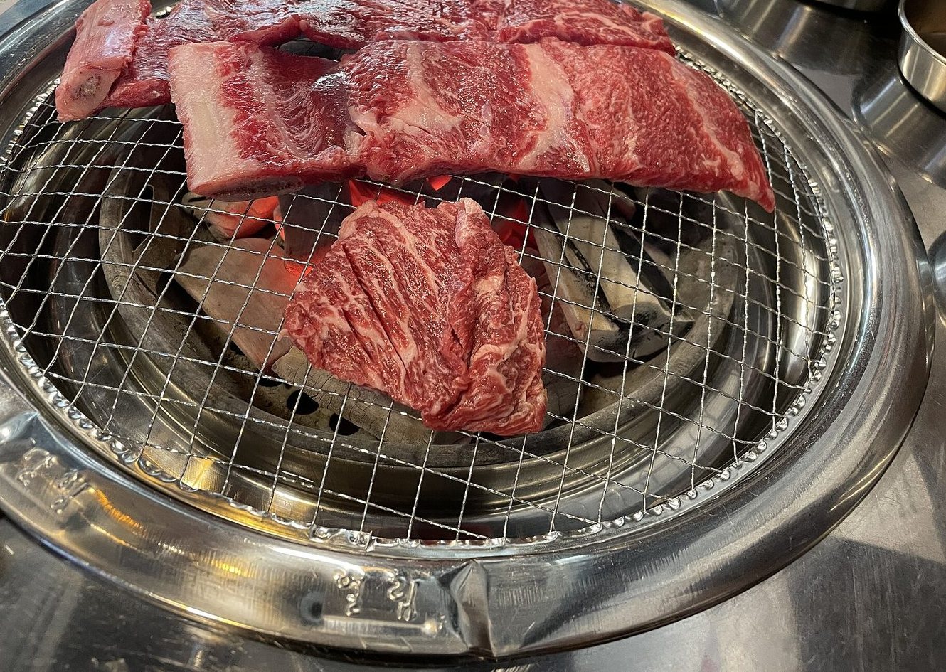 Émincé de bœuf marbré posé sur la grille du barbecue coréen